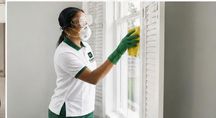 Emphile staff member in branded uniform cleaning window shutters